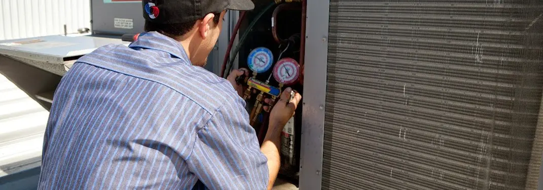 HVAC technician servicing a condenser unit in Columbus